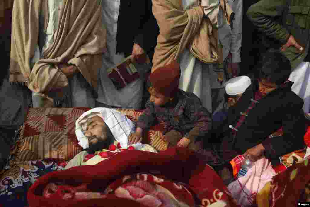 Children sit beside one of 14 victims whom tribesmen said were killed by security forces in the northwestern Pakistani city of Peshawar. Protesters said men in uniforms raided their homes in the Sipah Alam Goodar area overnight and shot the villagers dead. Villagers laid the bullet-riddled bodies of their relatives in front of the governor&#39;s house in Peshawar. (Reuters/Fayaz Aziz)