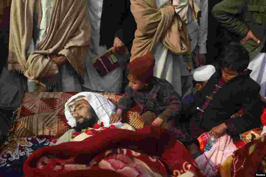 Children sit beside one of 14 victims whom tribesmen said were killed by security forces in the northwestern Pakistani city of Peshawar. Protesters said men in uniforms raided their homes in the Sipah Alam Goodar area overnight and shot the villagers dead. Villagers laid the bullet-riddled bodies of their relatives in front of the governor's house in Peshawar. (Reuters/Fayaz Aziz)