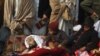 Children sit beside the body of one of the victims during a protest in front of the government offices in Peshawar.