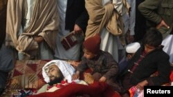 Children sit beside the body of one of the victims during a protest in front of the government offices in Peshawar.