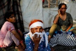 Hindu refugees from Pakistan pose for a photograph as they sit outside their makeshift hut at a Hindu refugee settlement situated in a woodland area near Signature Bridge.