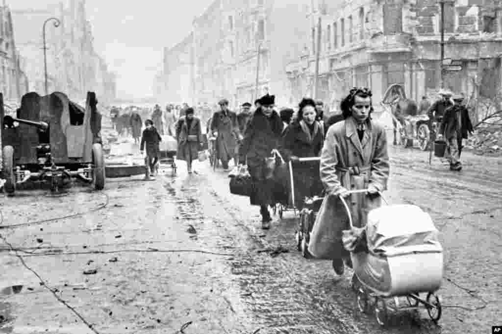 Civilians walking along a decimated Berlin street. &nbsp; Thousands of German women were raped by Soviet soldiers, forcing many female Berliners&nbsp;to hide in the evening during &ldquo;hunting hours&rdquo; and emerge only in the early morning when Soviet troops were asleep.