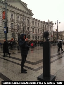 Прохожий фотографирует памятник Павленскому, установленный напротив бывшего здания КГБ Литовской ССР
