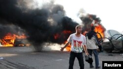 Antigovernment protester shouts slogans in front of burning cars during clashes with pro-government supporters in Alexandria on December 14. 