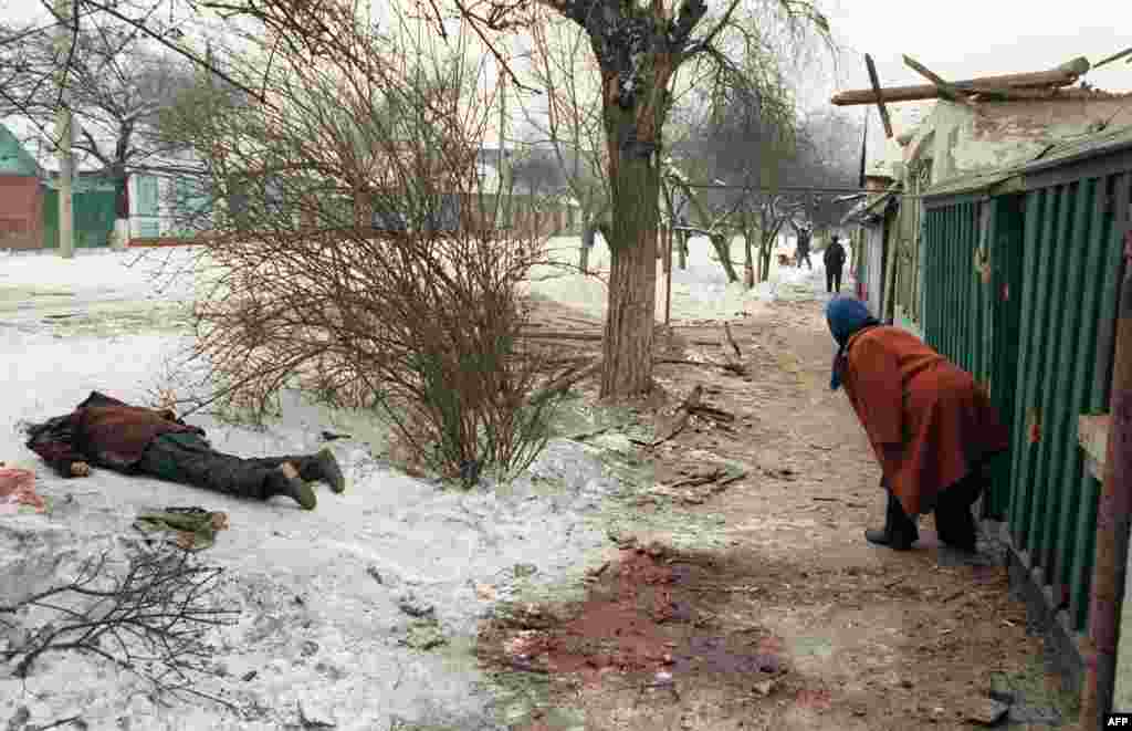 A local woman steps out of her home, and near a dead body. From points around the city, Russian forces bombard Grozny. Thousands of rounds of artillery rain down on the Chechen capital.