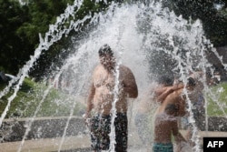 Oameni sub arteziană în zona de agrement Madrid Rio, pe 28 iunie 2025.