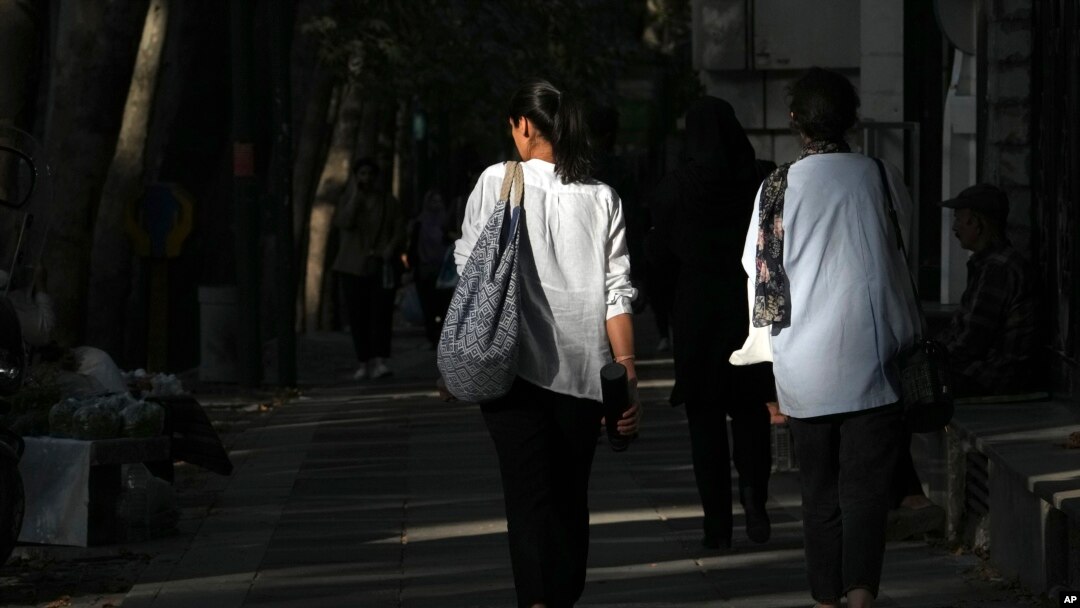 Iranian women walk on a Tehran street without wearing the mandatory head scarves.