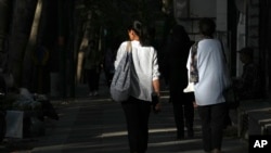 Iranian women walk on a Tehran street without wearing the mandatory head scarves.