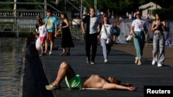 Një burrë shtrihet pranë një shatërvani në një park gjatë motit të nxehtë në Moskë, Rusi, 2 korrik 2024.