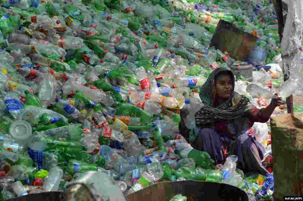 Loharda pakistanly işçi plastik çüýşeleri saýlaýar. (AFP/Arif Ali)