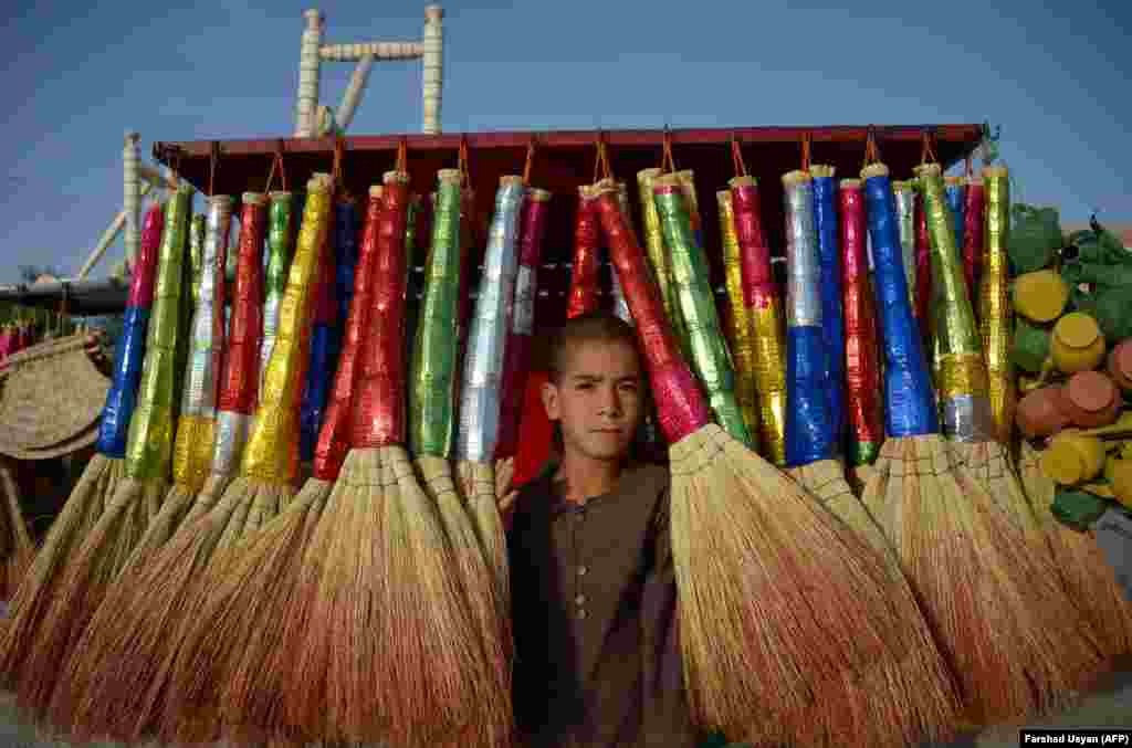 Afghan vendor Rafi, 9, poses for a photograph as he sells brooms at a roadside stall in Mazar-e Sharif. (AFP/Farshad Usyan)