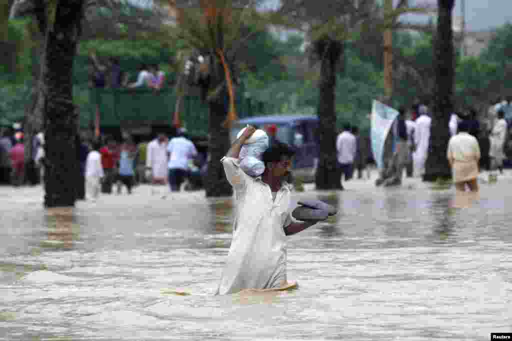 A man carries his belongings on his shoulder while wading through floodwaters outside of Karachi. 