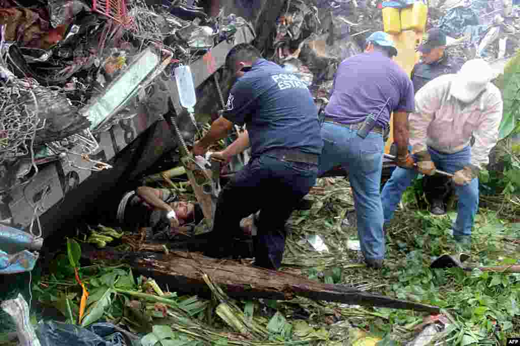 Mexican state police officers help people trapped after a train, known as "The Beast," derailed near Huimanguillo, Tabasco State, Mexico. The cargo train, which carries scrap metal and U.S.-bound migrants who pay smugglers for the right to sit atop freight cars, derailed in a swampy area of southeastern Mexico, killing at least six people. (AFP/"Tabasco Hoy")
