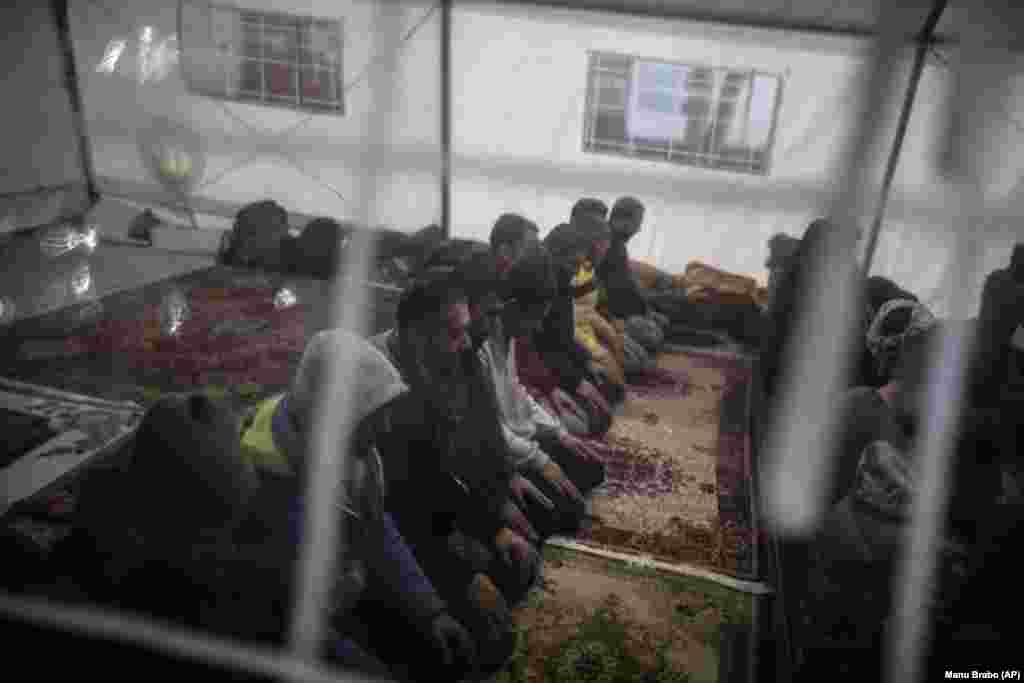 Një grup migrantësh, kryesisht nga Pakistani dhe Afganistani luten në një xhami të improvizuar në qendrën e pritjes së përkohshme të ngritur nga Organizata Ndërkombëtare për Migrantët në Bihaq.&nbsp;