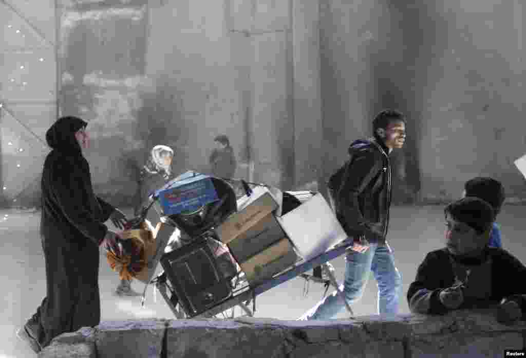 A man pulls a trolley containing belongings as a woman walks behind him in Aleppo, Syria. (Reuters/Ammar Abdullah)