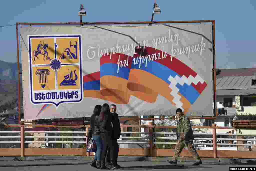 Locals walk past a billboard sporting the separatist Nagorno-Karabakh flag.