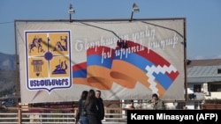 Nagorno Karabakh --Pedestrians walk past a poster bearing a flag of Nagorno-Karabakh in Stepanakert, November 24, 2020