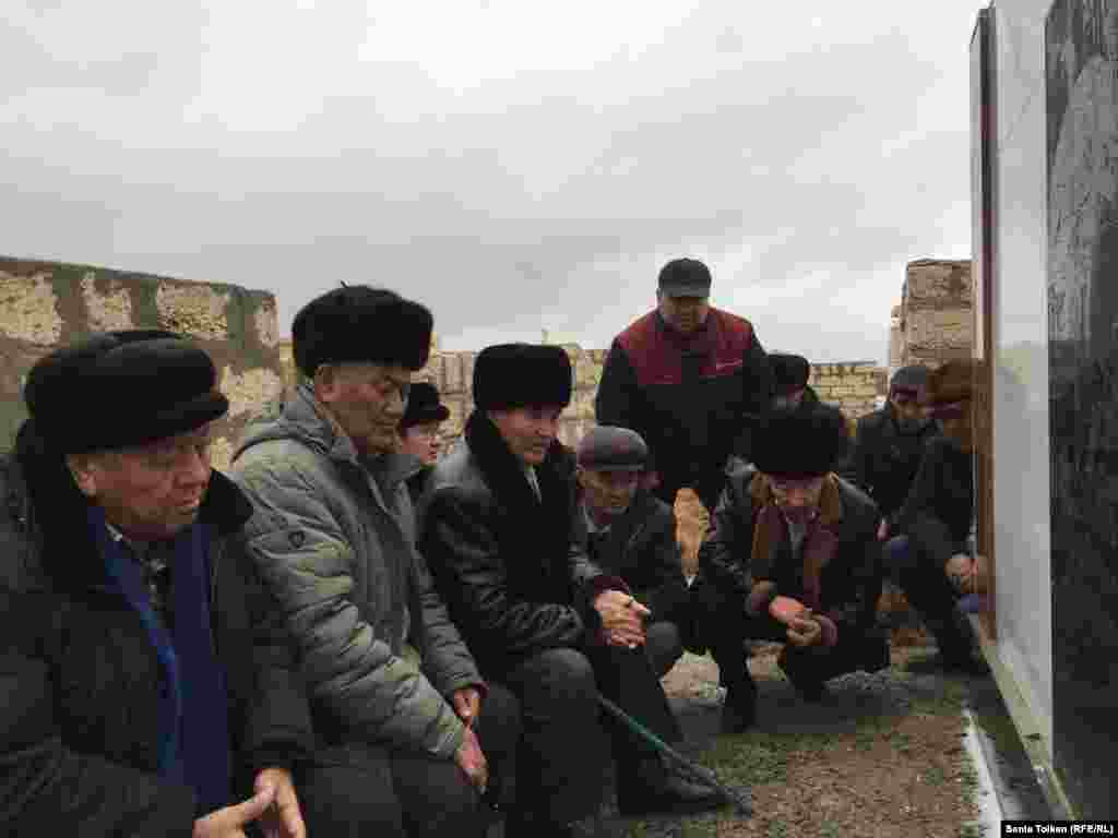 Мужчины слушают слова молитвы на кладбище на поминках по жертвам разгона демонстрации нефтяников в Жанаозене.&nbsp;