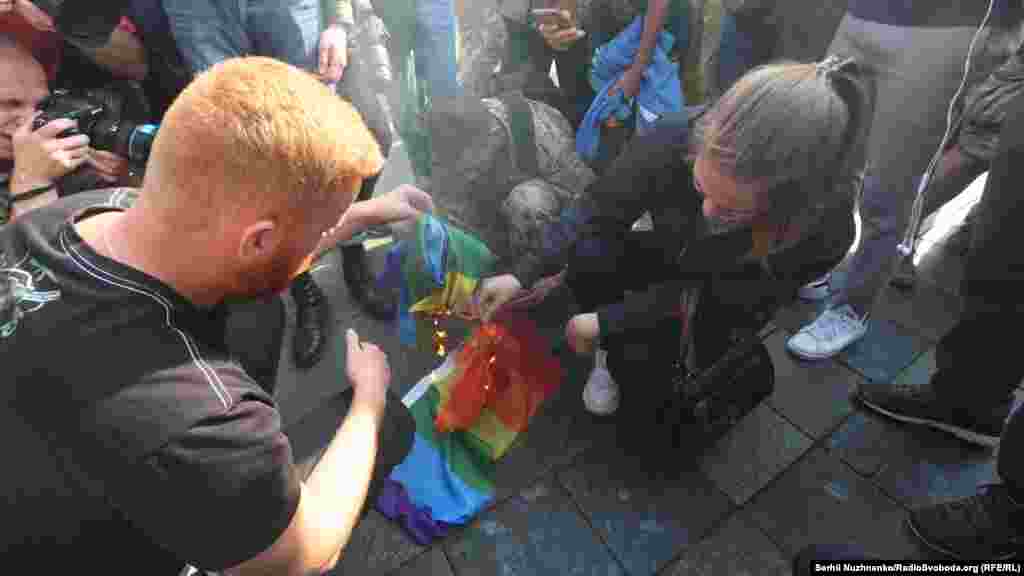 Праціўнікі маршу паляць сьцяг ЛГБТ-супольнасьці.