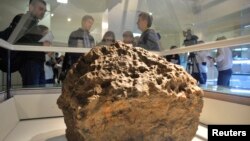 Журналисты рассматривают фрагмент метеорита, который, по сообщениям ученых и властей, был извлечен со дна озера Чебаркуль. Челябинск, 18 октября 2013 года.
