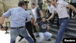 Azerbaijani plainclothes police officers detain an opposition supporter during an antigovernment protest in central Baku on May 21.