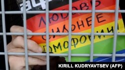 A gay rights activist holds a poster reading "Love is stronger than homophobia!" while sitting inside a police van after his detention at a rally in central Moscow in 2013.