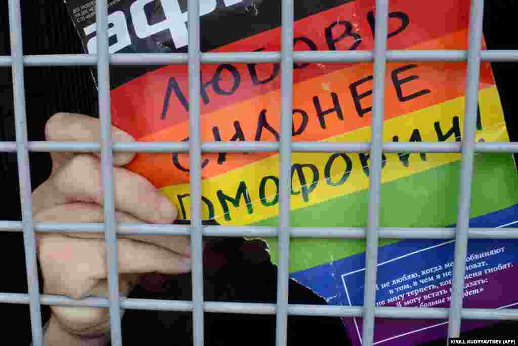 Un activist rus pentru drepturile LGBT ține un afiș pe care scrie &bdquo;Iubirea este mai puternică decât homofobia!&rdquo; după ce a fost arestat, în timpul unui miting neautorizat pentru drepturile homosexualilor din centrul Moscovei, în 25 mai 2013.