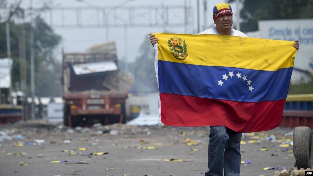 A demonstrator holds a Venezuelan flag on the bridge in Urena, Venezuela, on the border with Colombia.