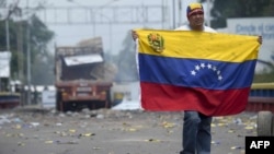 A demonstrator holds a Venezuelan flag on the bridge in Urena, Venezuela, on the border with Colombia.