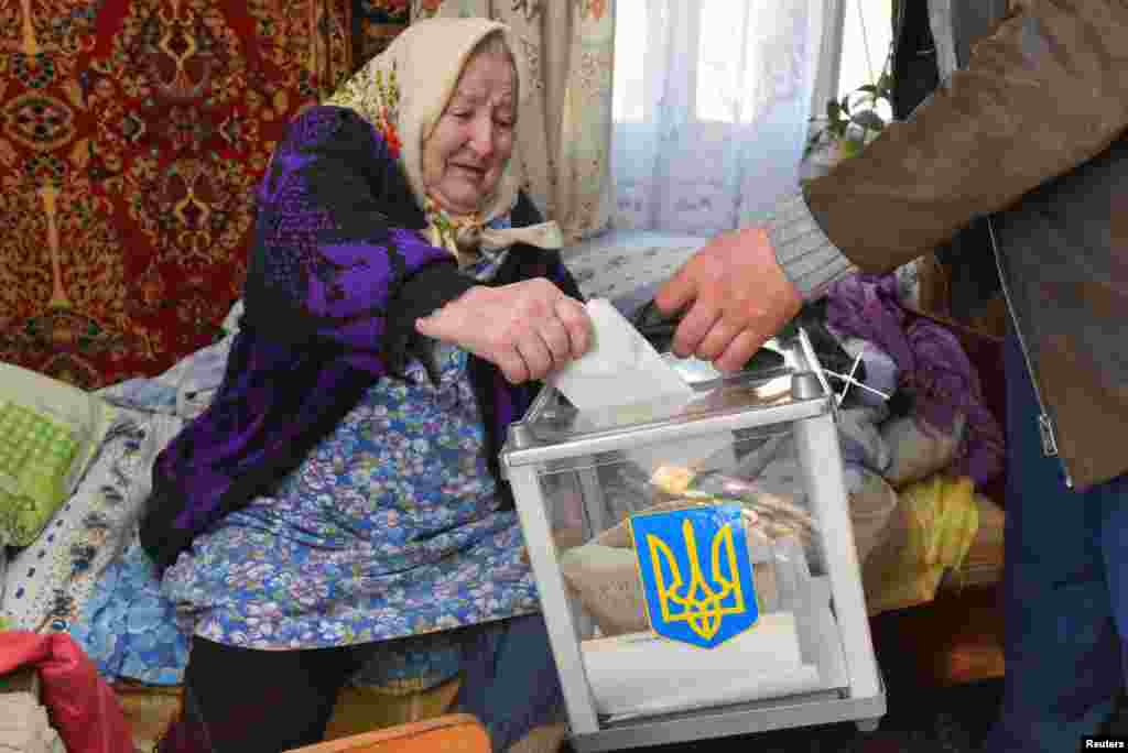 Місцева жителька кидає бюлетень в мобільний ящик для голосування у селі Загір'я на Львівщині