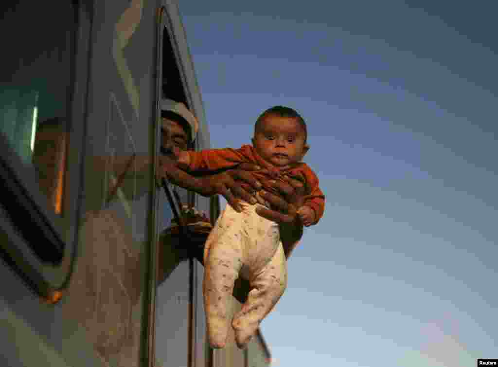 A migrant holds a baby outside the window of a train while waiting to depart from the railway station in Tovarnik, Croatia. (Reuters/Marko Djurica)