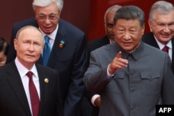 Очільник Росії Путін дивиться туди, куди пальцем показує очільник Китаю Сі Цзіньпін перед військовим парадом з нагоди 80-ї річниці перемоги над Японією та закінчення Другої світової війни. Пекін, 3 вересня 2025 року