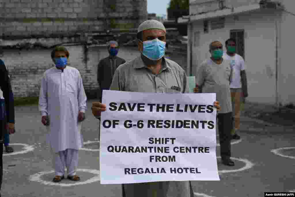 Residents of Pakistan&#39;s capital, Islamabad, wearing masks and practicing physical distancing hold placards as they protest against a quarantine center that was set up in their neighborhood on April 19.
