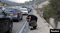 Israelis take shelter at the side of a highway as a siren sounds near Abu Ghush.