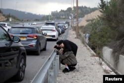 Ysraýylyň ýaşaýjylary Abu Ghuşyň golaýynda howa hüjüm sirenalary ýaňlanan mahaly, köçäniň ýakasynda pena tutunýarlar