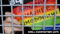 A gay rights activist holds a poster reading "Love is stronger than homophobia!" while sitting inside a police van after his detention at a rally in central Moscow in 2013.