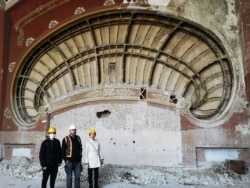 Architect Radu Cornescu, Apollon Cristodulo, and Laura Voicila (left to right) at the shell wall inside the casino where the secret political prisoner note was found.