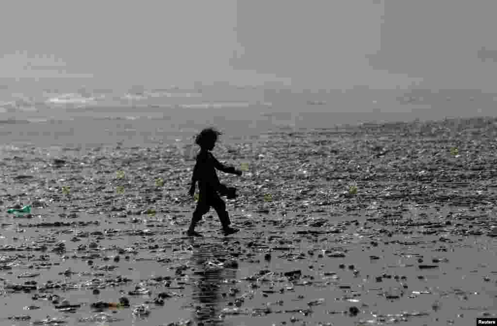 A girl walks through rubbish left by waves along Clifton Beach in Karachi, Pakistan. (Reuters/Akhtar Soomro)