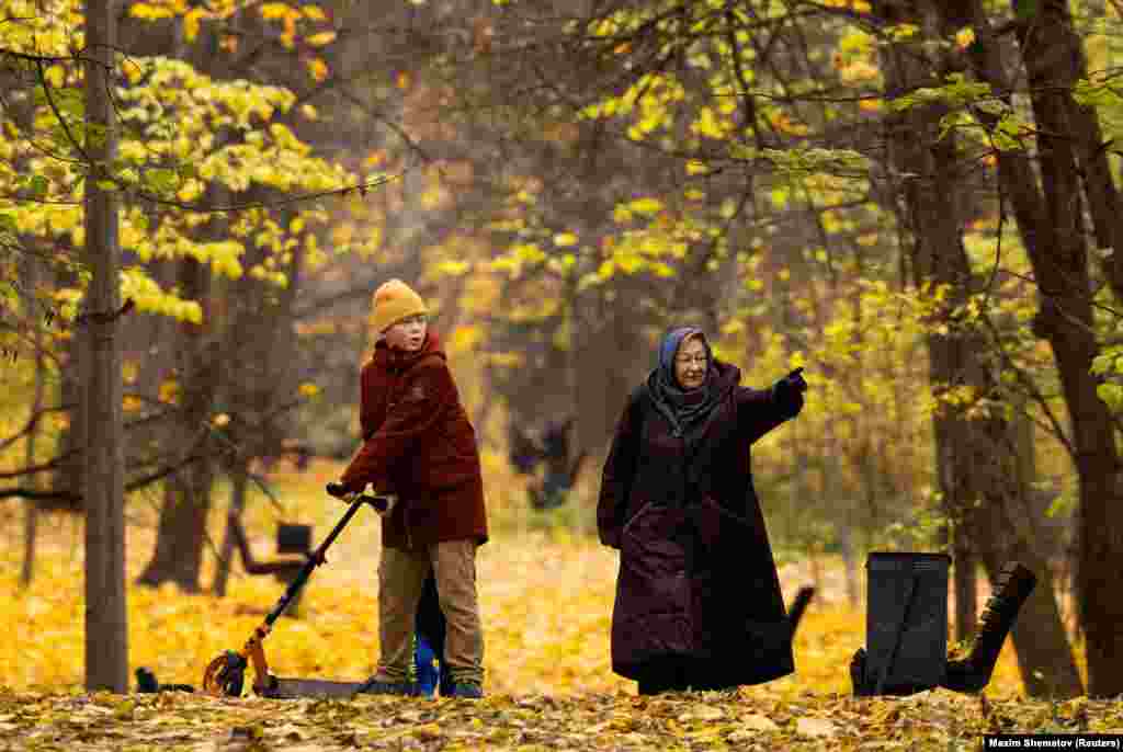 An elderly woman walks with a boy in a park on an autumn day in Moscow.