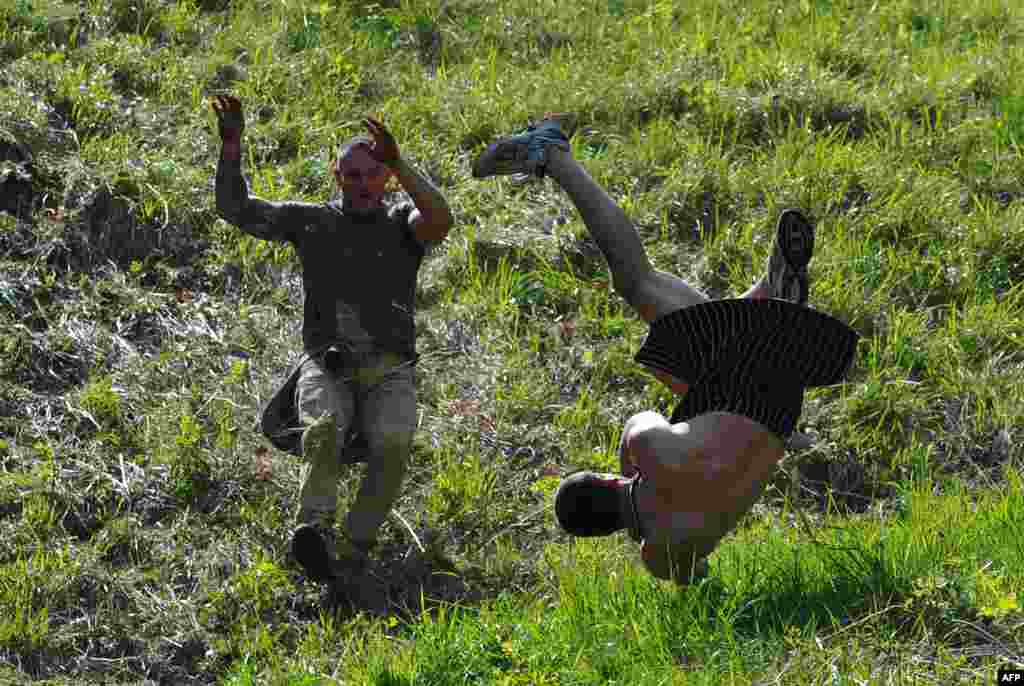 A competitor tumbles down Coopers Hill in pursuit of a fascimile round of Double Gloucester cheese during the annual cheese-rolling near the village of Brockworth in western England. With a disputed history dating back to at least the 1800s, the event involves hordes of fearless competitors chasing a large cheese down a very steep hill. (AFP/Carl Court)