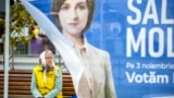 An elderly woman sits on a street bench behind a party campaign tent in downtown Chisinau ahead of a runoff in the presidential election. 