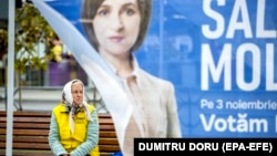 An woman sits on a street bench in downtown Chisinau behind a campaign tent for President Maia Sandu on October 31. 