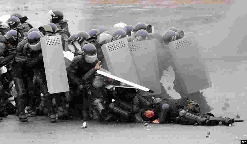 Riot policemen shield themselves during clashes with opposition protesters.