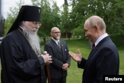Vladimir Putin discută cu arhiepiscopul Alexei de Sitka și Alaska, după o ceremonie de depunere de flori la mormintele soldaților sovietici din Cimitirul Național Fort Richardson, lângă Anchorage, Alaska, SUA, 15 august 2025.