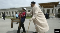 An Uzbek boy carries a chair as he assists an elderly believer to get to a mosque for Friday prayers in Tashkent.