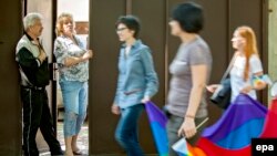 Residents look out from the doorway of their home as LGBT supporters pass during a march for human rights in downtown Chisinau in May.