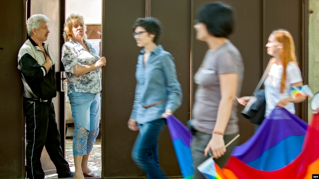 Residents look out from the doorway of their home as LGBT supporters pass during a march for human rights in downtown Chisinau in May.