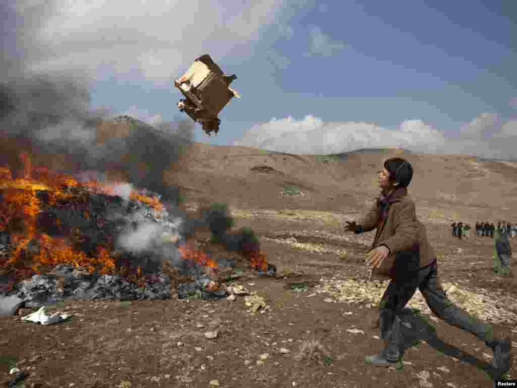 An Afghan boy throws a box on a burning pile of confiscated narcotics in Kabul. - Photo by Ahmad Masood for Reuters 