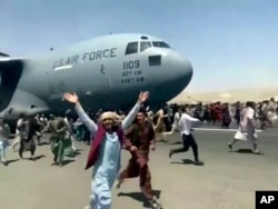 Hundreds of people run alongside a U.S. Air Force C-17 transport plane as it moves down a runway of the international airport in Kabul on August 16, 2021.