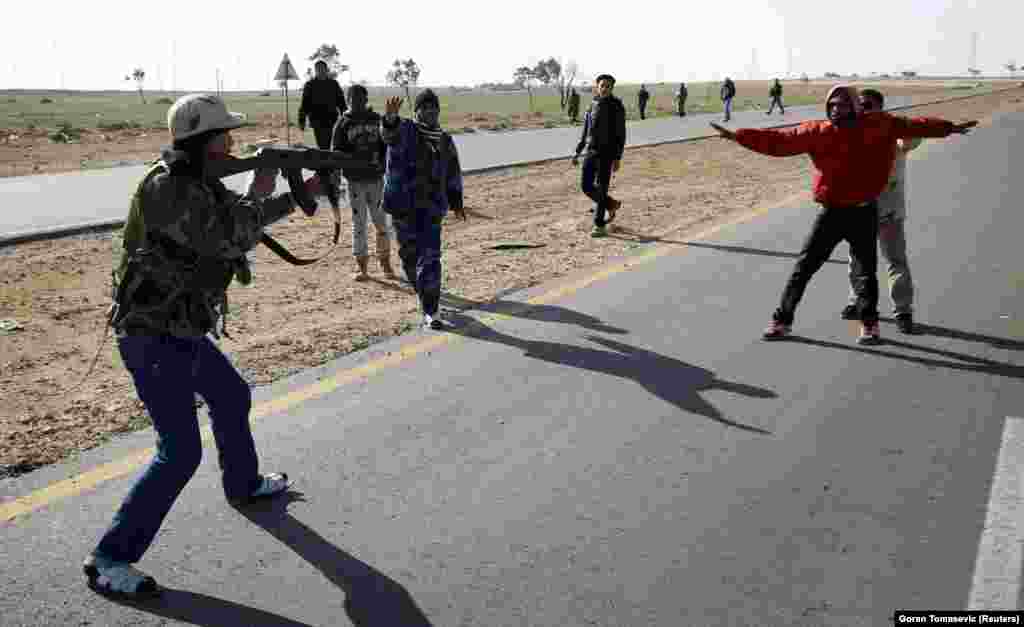 During the 2011 conflict that followed mass protests against Libyan leader Muammar Qaddafi, a rebel fighter points his gun at a suspected Qaddafi supporter.